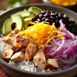 Close-up of a chicken and rice burrito bowl with fresh ingredients and vibrant colors.