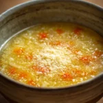 Close-up of Italian Penicillin Soup with chicken and herbs in a bright setting.