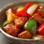 Close-up of Sweet and Sour Chicken with a glossy sauce and vibrant colors.
